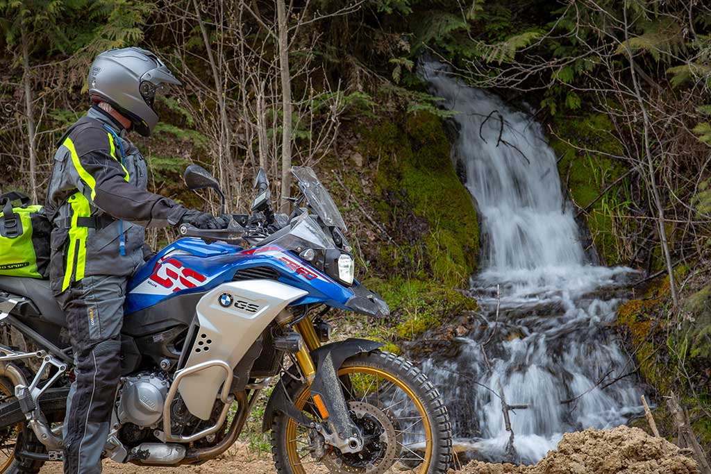 biker looking at a waterfall coming down a mountain